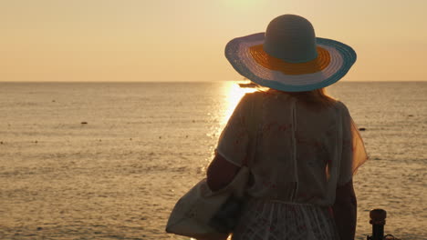 Un-Turista-Delgado-Se-Encuentra-Con-El-Amanecer-En-El-Mar-Con-Una-Bolsa-En-El-Hombro-Y-Un-Sombrero-De-Ala-Ancha