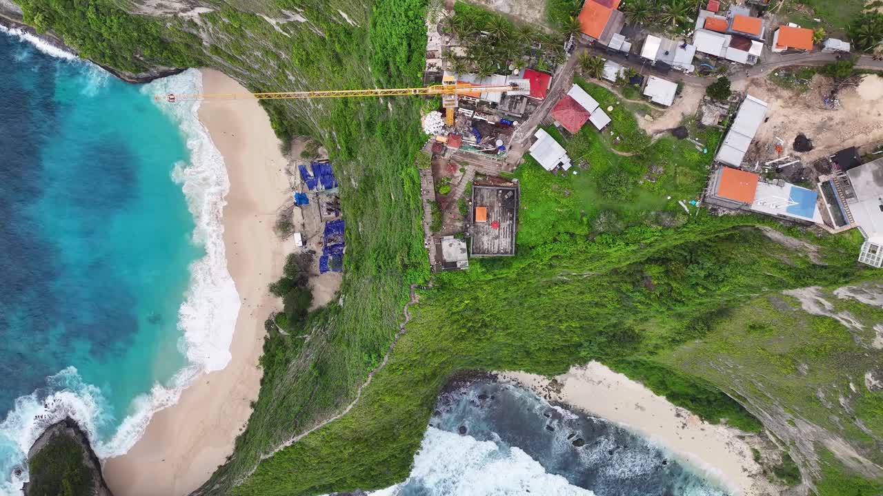 Aerial top down of crane on cliff top Kelingking Beach building a lift. Controversial project, Bali.