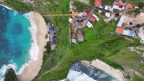 aerial top down of crane on cliff top kelingking beach building a lift. controversial project, bali.