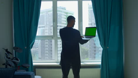 man working on laptop by window