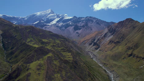 drone shot of annapurna green hills in nepal divided by river in between along with annapurna mountain