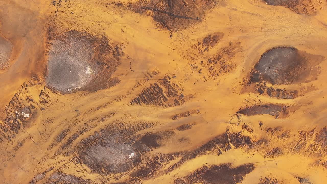 Top-down aerial view of the yellow-toned Þjórsá River in Iceland, carving through volcanic terrain and creating surreal patterns across the landscape.