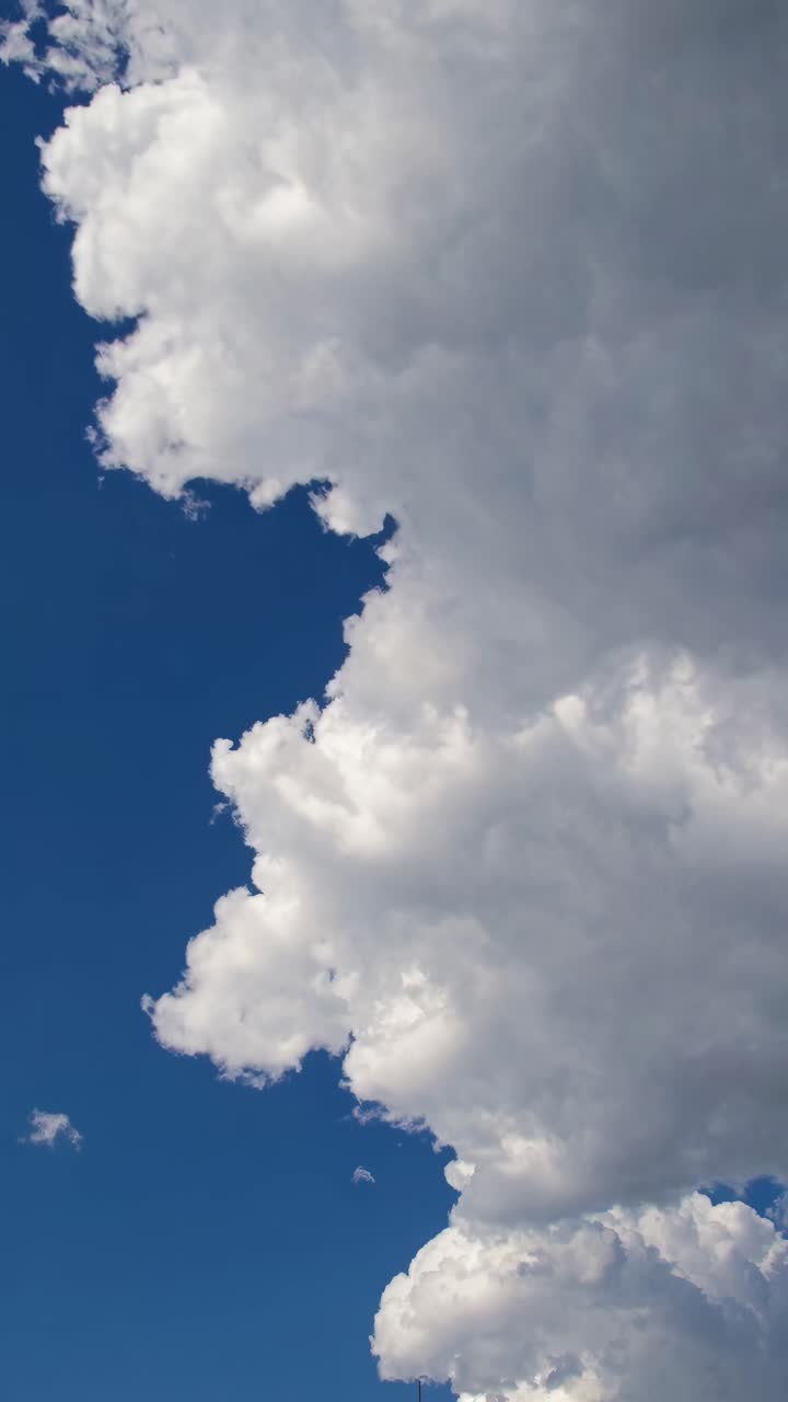Dramatic upward angle video of fluffy white clouds against a deep blue sky, capturing the vastness