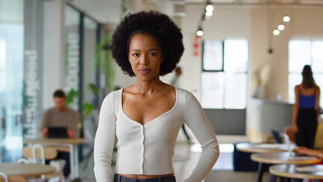 portrait of smiling businesswoman standing in busy modern open plan office