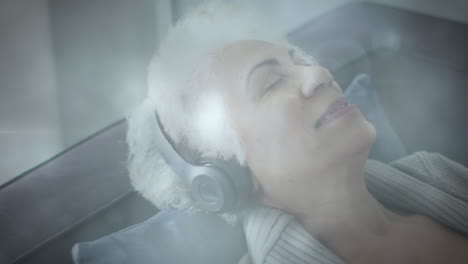 animation of glowing light over happy senior woman listening to music with headphones