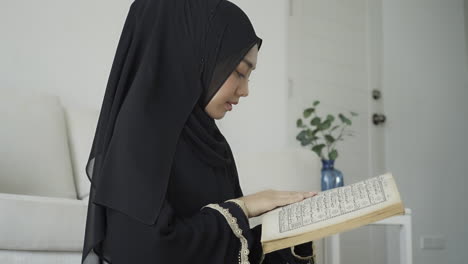 an asian muslim woman reciting salah or salat al-fatiha passage of the qur'an, in a single act of sujud called a sajdah or prostrations at home