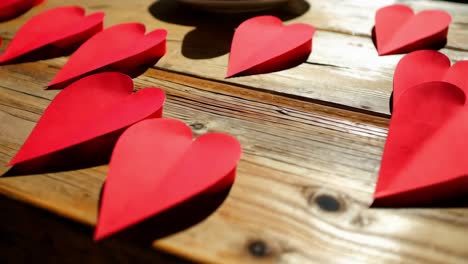 corazones de papel rojo en una mesa de madera