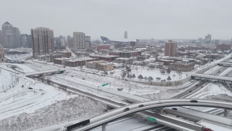 aerial view of snowy minneapolis, featuring highways, modern buildings, and the us bank stadium under an overcast winter sky.