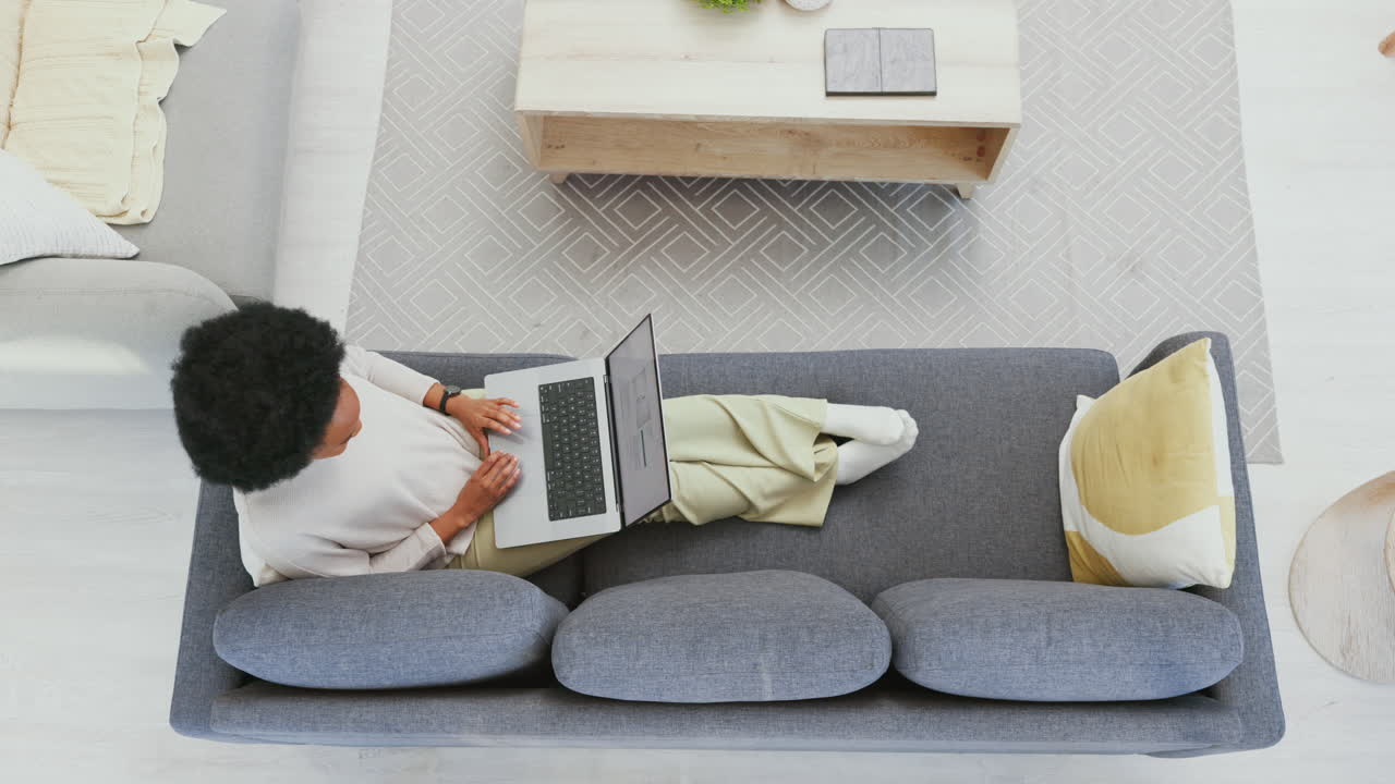 Woman working on laptop while relaxing at home