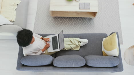 mujer trabajando en una computadora portátil mientras se relaja en casa