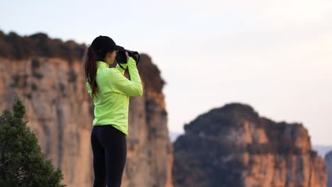 mujer joven fotografiando montañas en la cámara