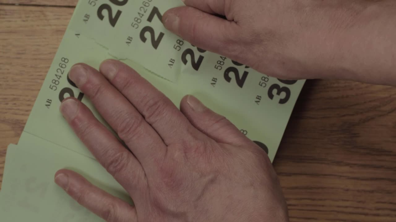 Hand tearing lottery tickets overhead shot