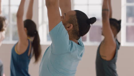 clase de yoga hombre hispano saludable practicando pose de guerrero disfrutando de un estilo de vida físico haciendo ejercicio con personas multirraciales en un estudio de entrenamiento