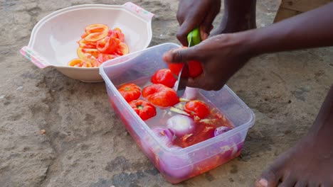 mujer lava y corta pimientos para la salsa que acompaña al banku
