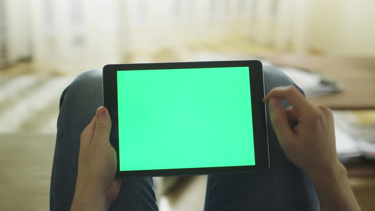 남자는 집에서 소파에 누워서 에서 랜드스케이프 모드에서 녹색 화면을 가진 태블릿을 사용하고 있습니다.