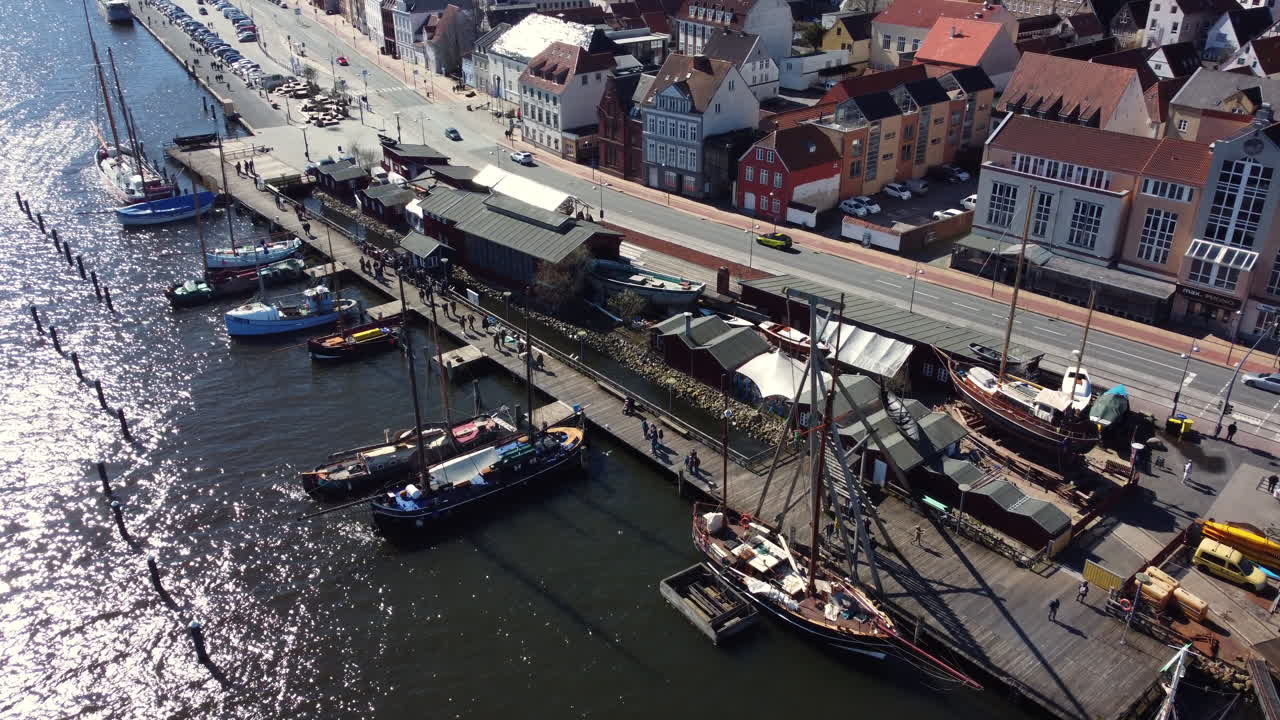 Aerial view of a harbor with historical ships and city buildings