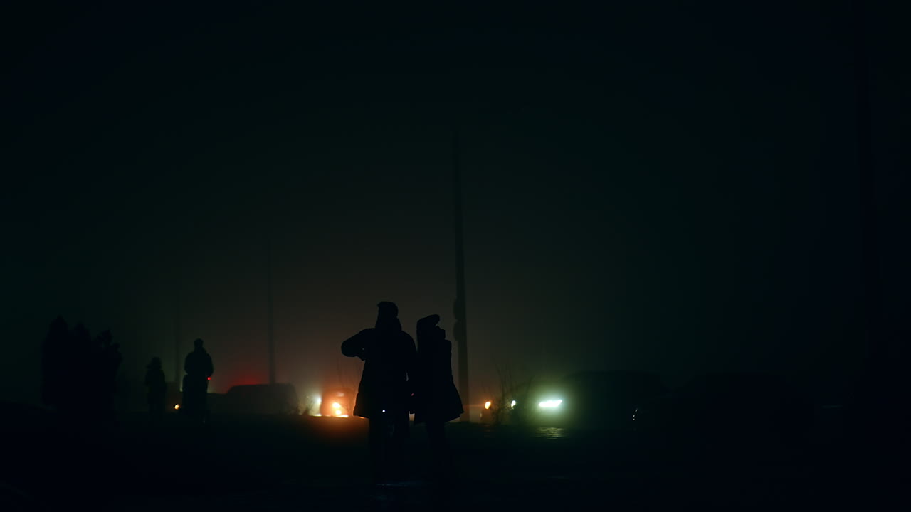 Silhouette of people walking in fog at night