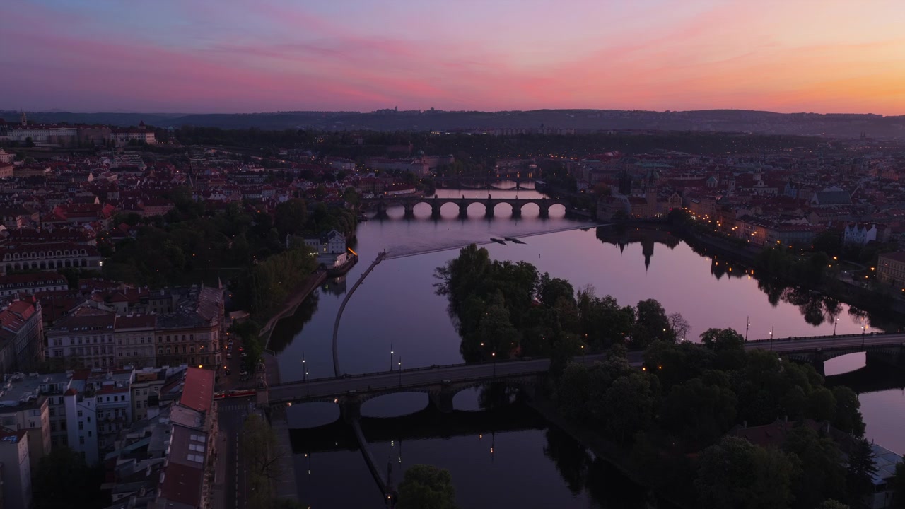 Veduta aerea con drone all'alba rosa-violacea del fiume Vltava con numerosi ponti, incluso il Ponte Carlo, il Castello di Praga e la Cattedrale di San Vito visibili in alto a sinistra, Praga, Repubblica Ceca