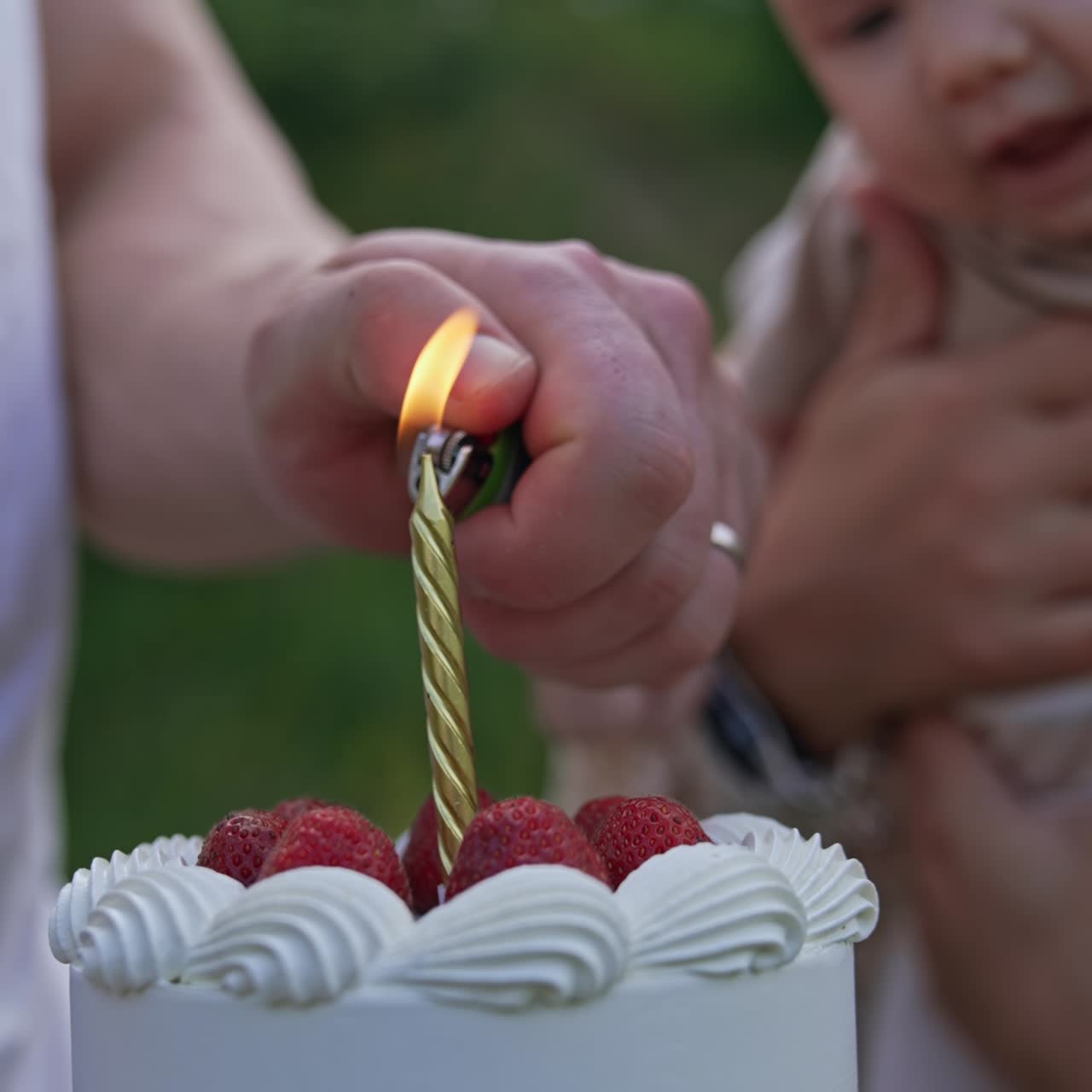 Beautiful creamy cake is given to a newborn baby. Male hand lighting a candle on the cake. Celebrating first month of child's life. Close up. Vertical screen