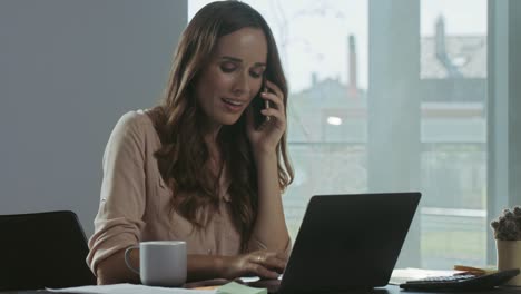 Young-woman-working-on-laptop.-Portrait-of-smiling-lady-chatting-mobile-phone