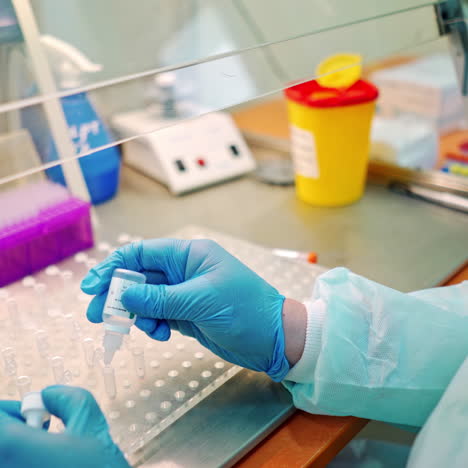 laboratory assistant working with vials in clinic. medical worker drops liquid into test tubes from small plastic jar.