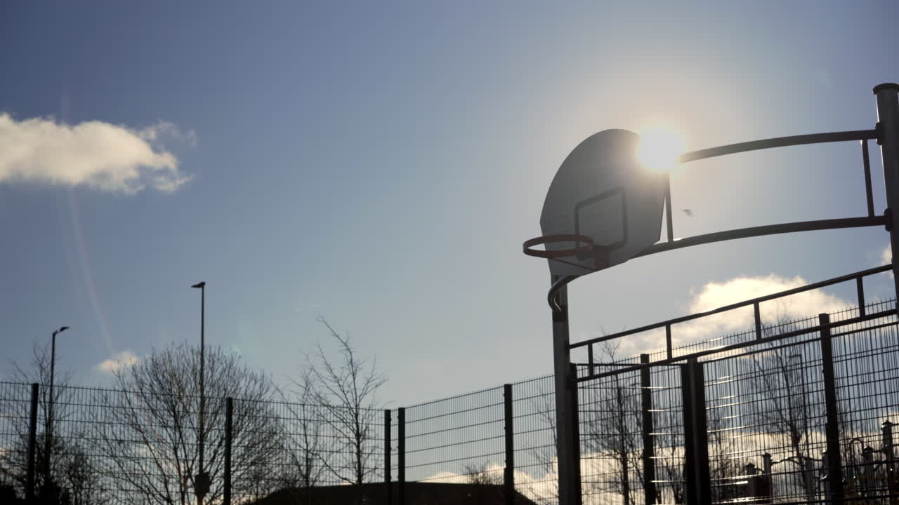 el sol brilla sobre el cielo azul del aro de baloncesto
