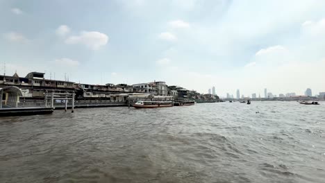 Paseo-En-Barco-Por-El-Río-Chao-Phraya-Con-La-Ciudad-Y-Otros-Barcos-En-Bangkok,-Tailandia,-Vista-Desde-El-Transporte-Acuático