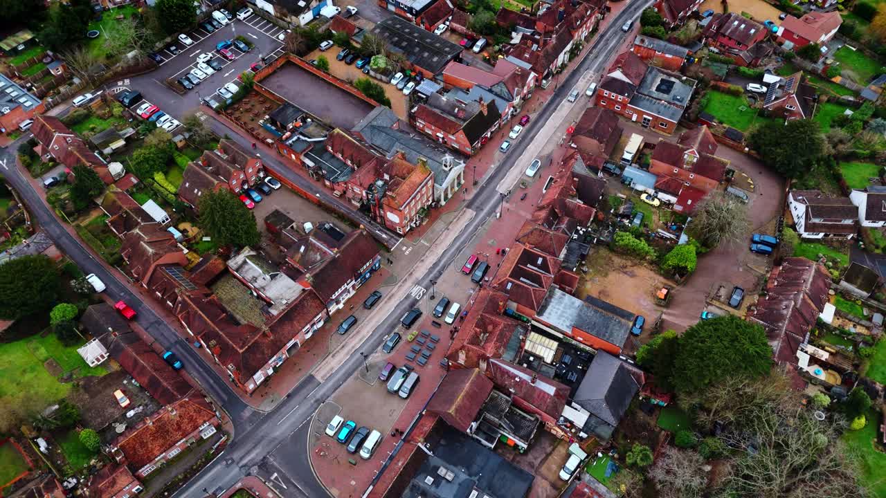 Ripresa aerea panoramica con drone sulla periferia di Southampton con le abitazioni del villaggio di Botley al tramonto in una nuvolosa e coperta giornata invernale, con auto che passano sulle strade sottostanti oltre le piccole case del paese.