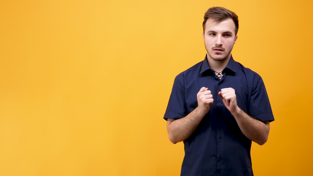 Man in blue shirt expressing emotions on yellow background
