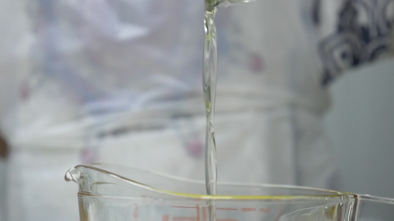Process for making handmade soap with an olive oil and glycerin base. Liquid, clear glycerin is poured over a mixture of bright yellow oil in a glass measuring cup