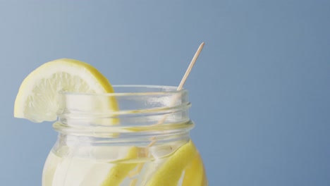 video of jar with lemonade and straw on blue background