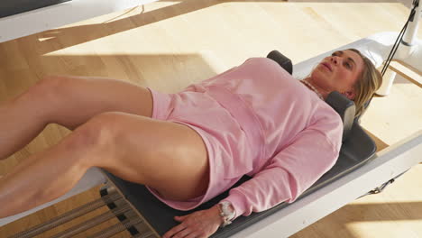 athletic woman doing stretching exercises over pilates reformer machine. high angle shot