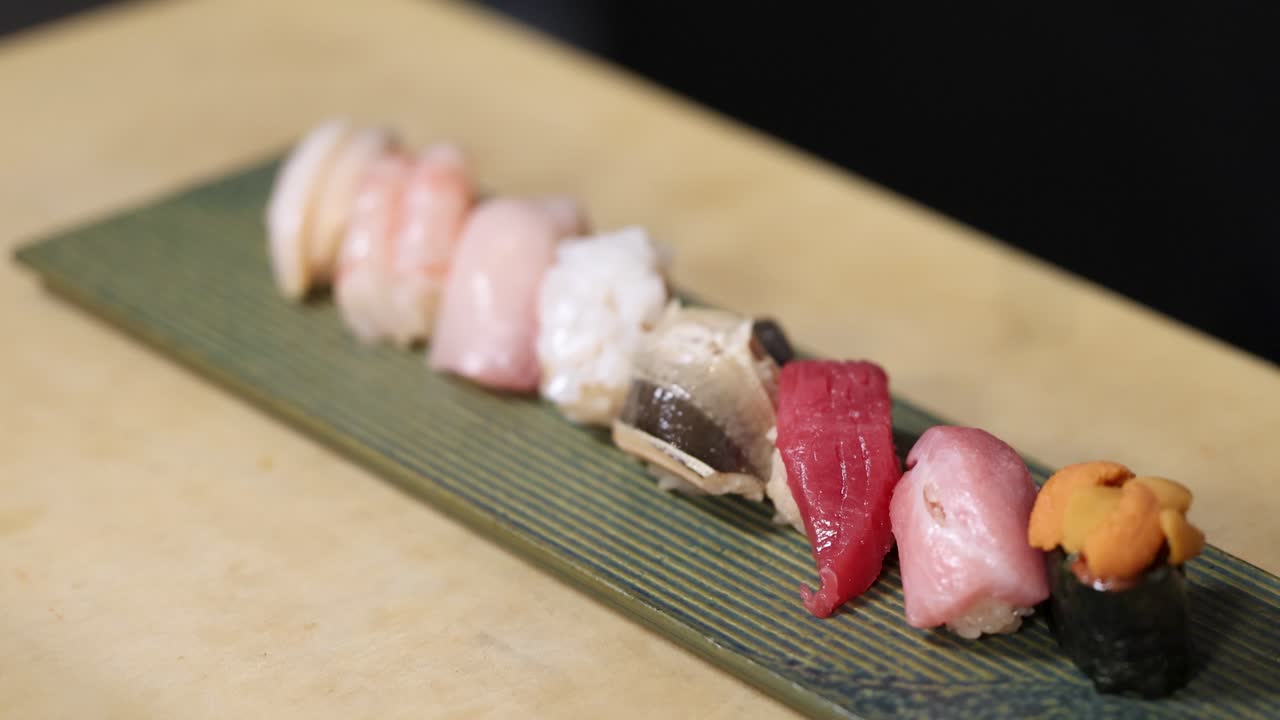 Un primo piano di un assortimento di nigiri sushi Premium disposto su un piatto di ceramica verde