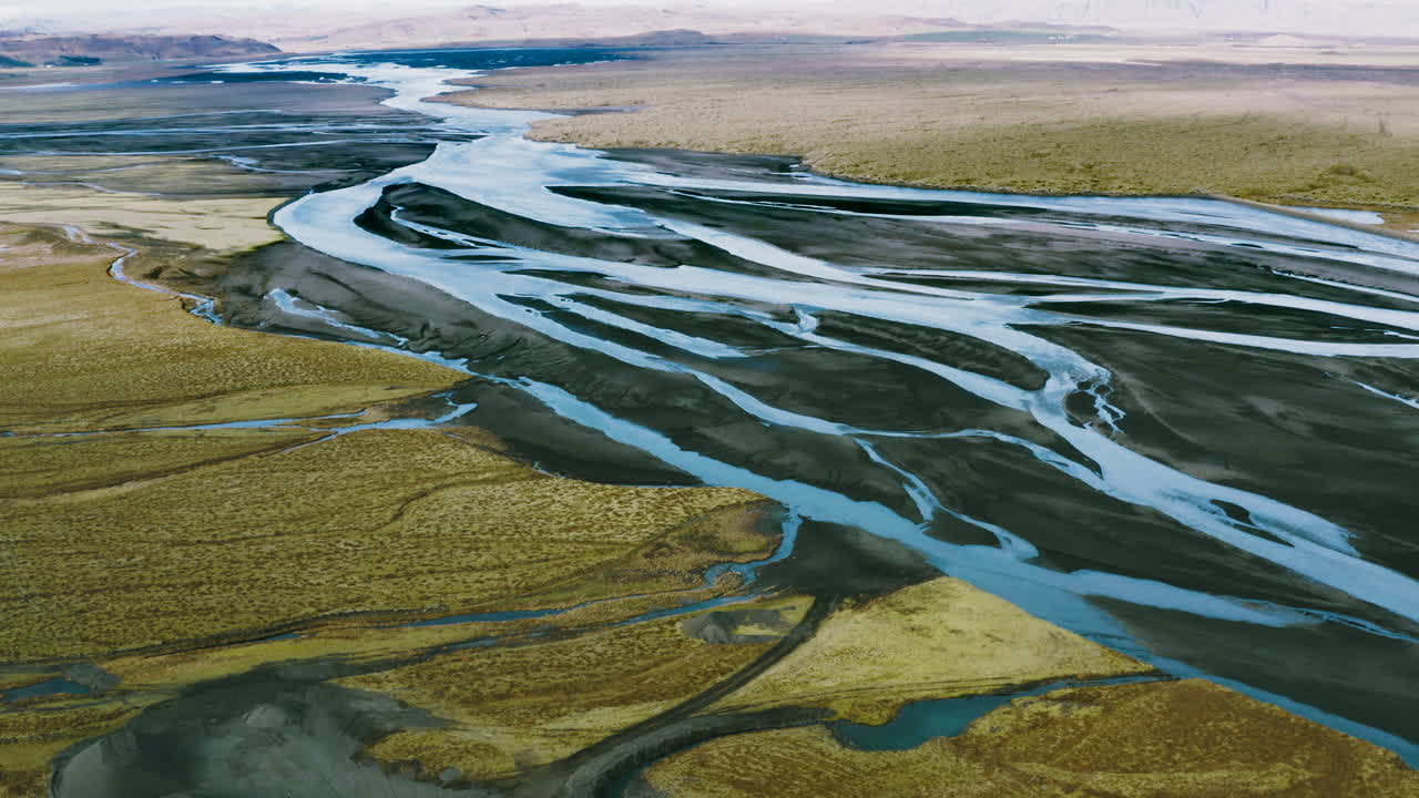Flying over a big delta formed by glacial rivers. Colorful rivers of Iceland, Icelandic river delta seen from above, Volcanic delta, Aerial view of a volcanic river.