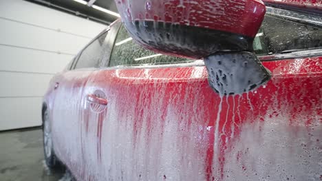 red car wash with flowing water and foam.