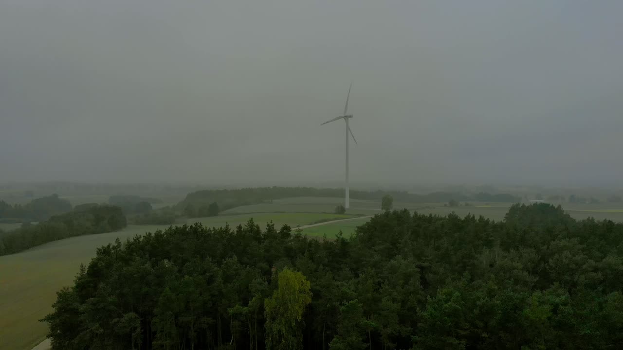 높은 나무 근처의 풍차 근처의 항공 영상, 지평선의 안개가 자욱한 기상 조건, 드론 촬영 비디오 4k
