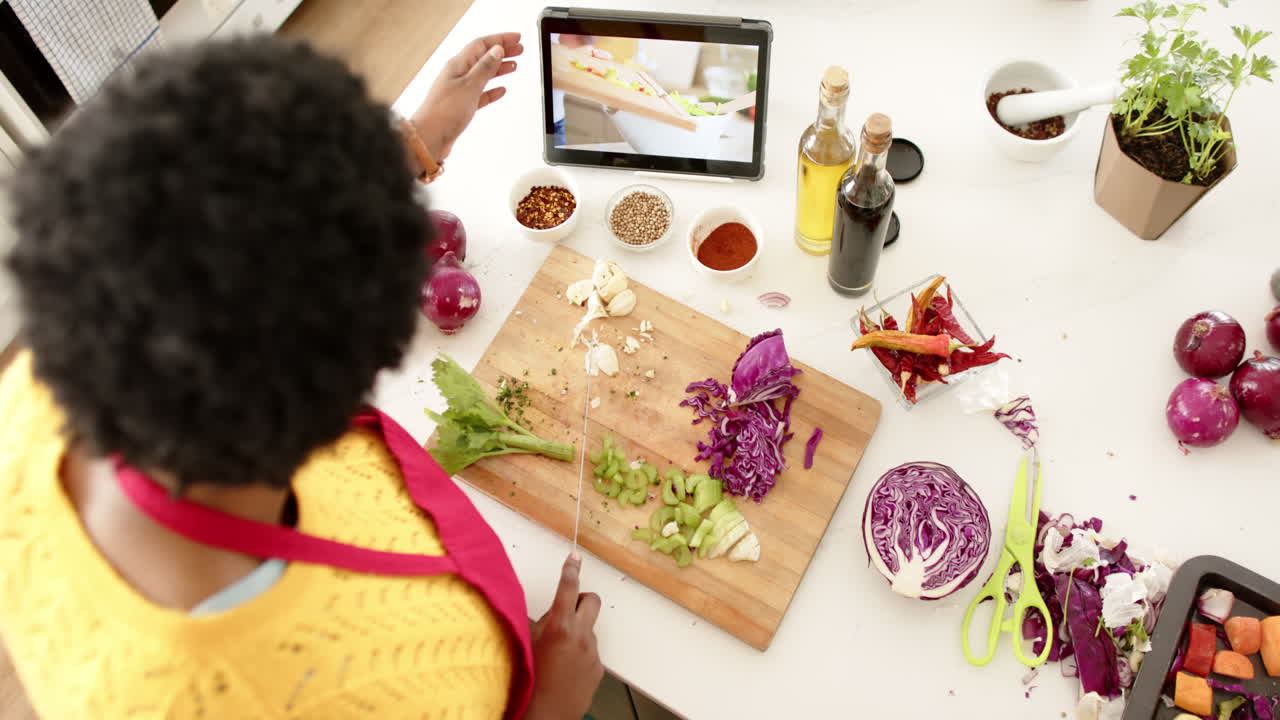African American woman follows a recipe on a tablet while cooking at home