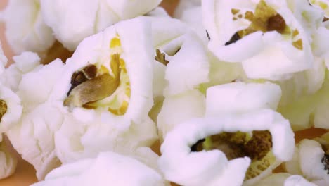 Detail-view-of-popcorn-rotating-on-orange-surface,-macro-shot-in-4k