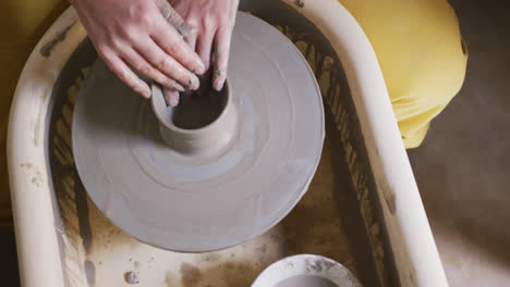 close up view of female potter creating pottery on potters wheel at pottery studio