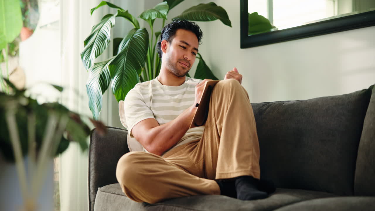 Young Man Writing in Notebook While Relaxing on Couch at Home