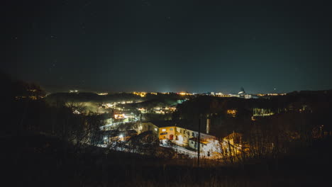 Un-Lapso-De-Tiempo-Nocturno-De-Una-Ciudad-Que-Muestra-Luces-Bailando-Y-Estrellas-Moviéndose-En-El-Cielo