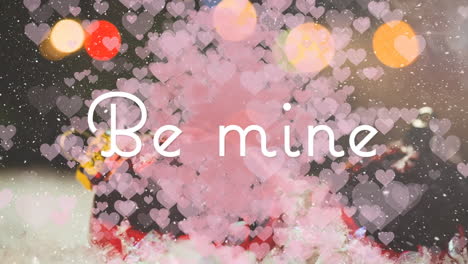 animation of be mine over hearts floating on blurred background