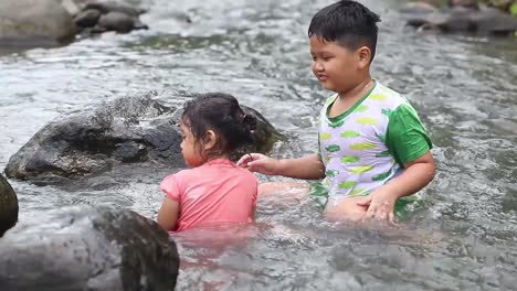 two asian children playing water in the river in a mountainous area