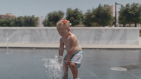 un niño pequeño divirtiéndose con el agua en la calle de la ciudad.
