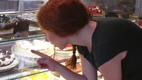 woman choosing cake at cafe