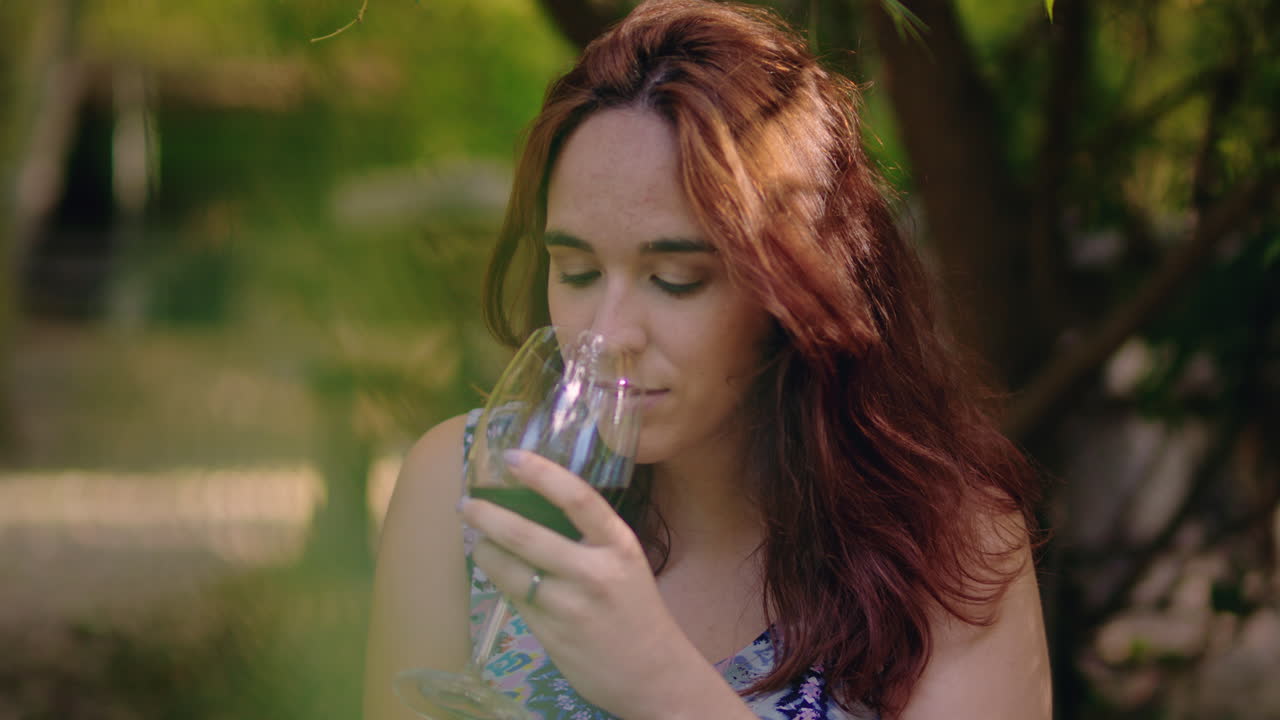 chica prueba un vaso de vino y sonríe en un parque de picnic medio tiro