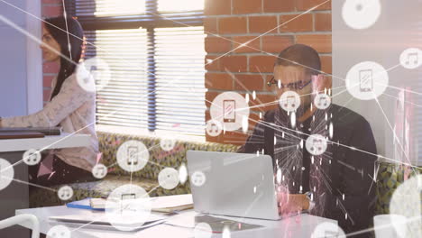 animation of network of connections over biracial man using laptop in office
