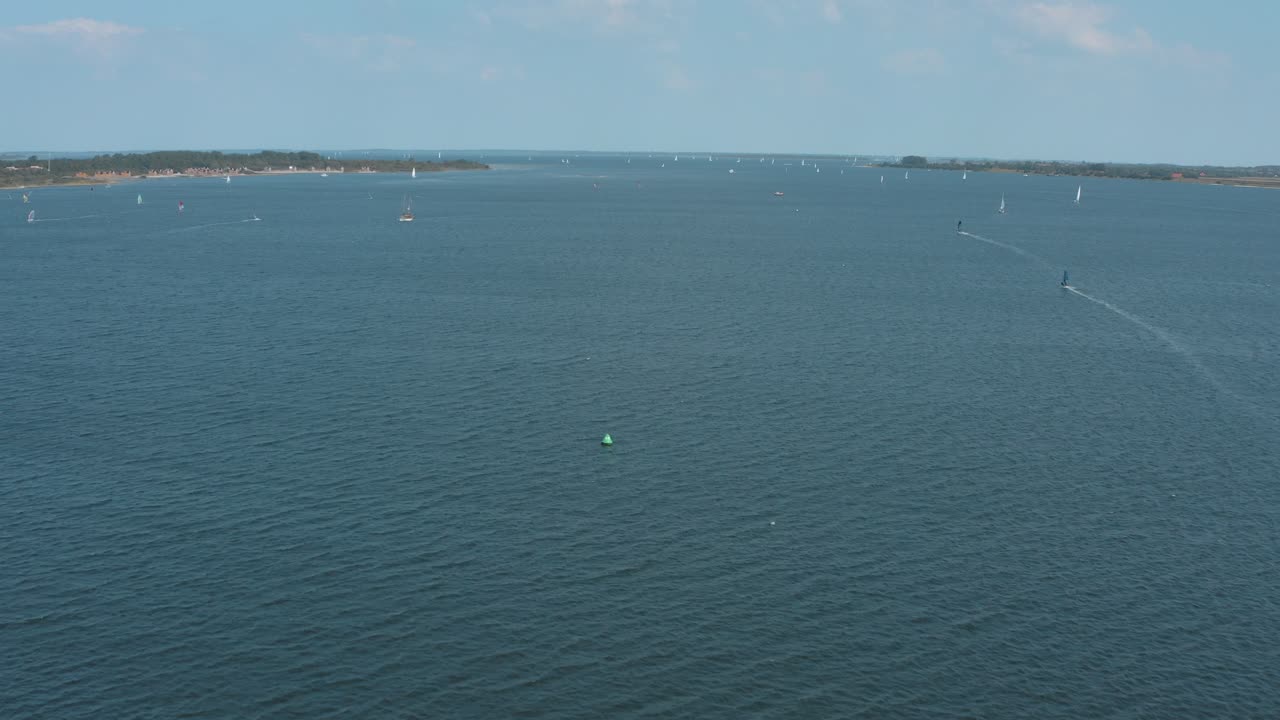 drone - toma aérea de un surfista en un mar azul, ondulado y ventoso en un día soleado con nubes blancas en una isla, 25p