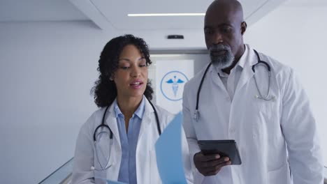 African-american-male-and-female-senior-doctors-discussing-over-medical-reports-at-hospital