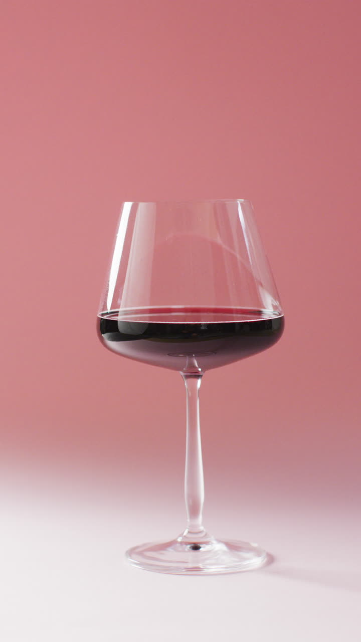 Vertical video of red wine glass on marsala background